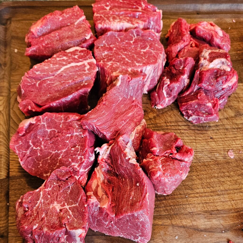 Raw cuts of filet mignon on a wooden cutting board.
