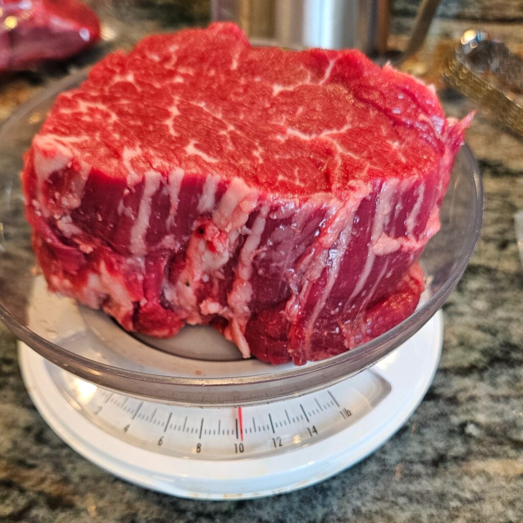 Raw cut of filet mignon on a meat weighing scale.