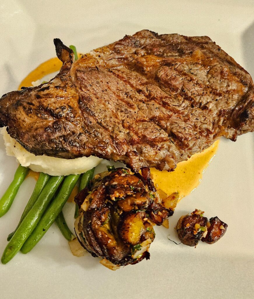 Ribeye steak on a plate with green beans.