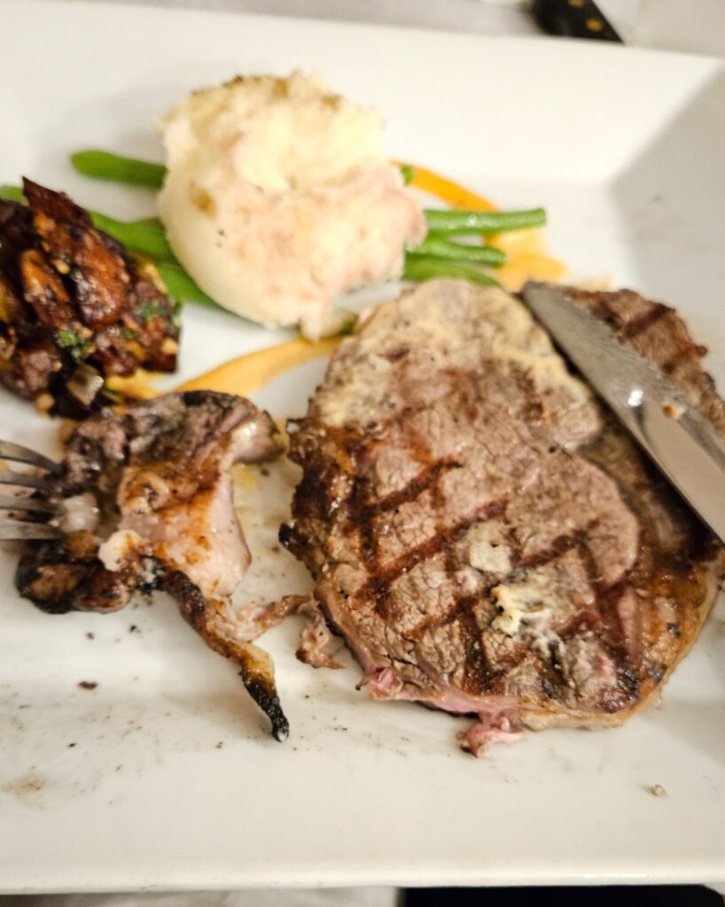 Ribeye steak on a plate with mashed potatoes and green beans.