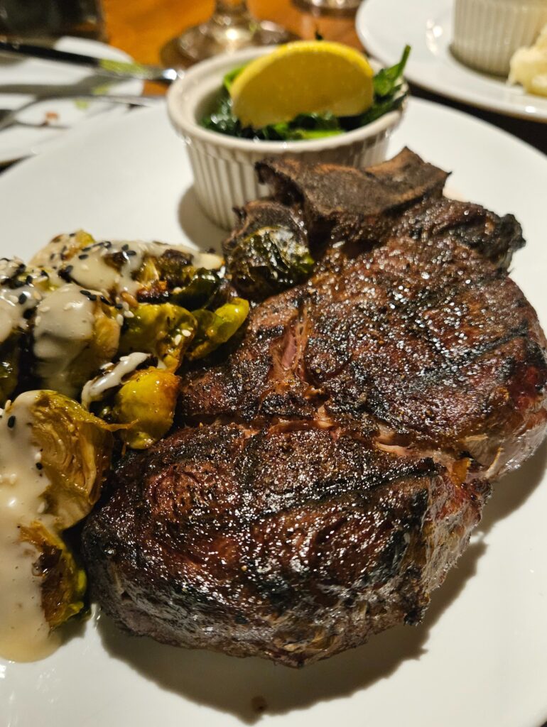 Ribeye steak on a plate with creamy brussels sprouts.