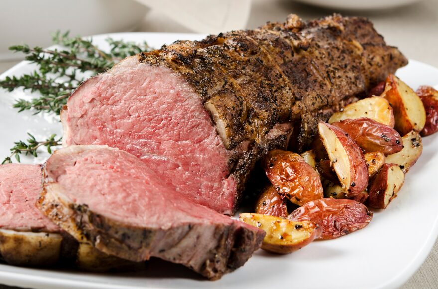Tenderloin served with roasted potatoes on a plate.