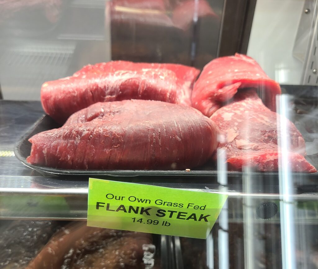 Flank steak on a tray on a meat counter.