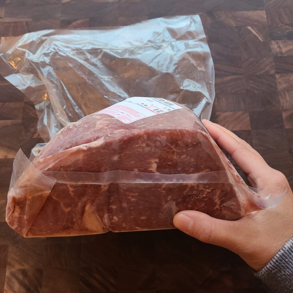 Hand holding bag of eye round steak.